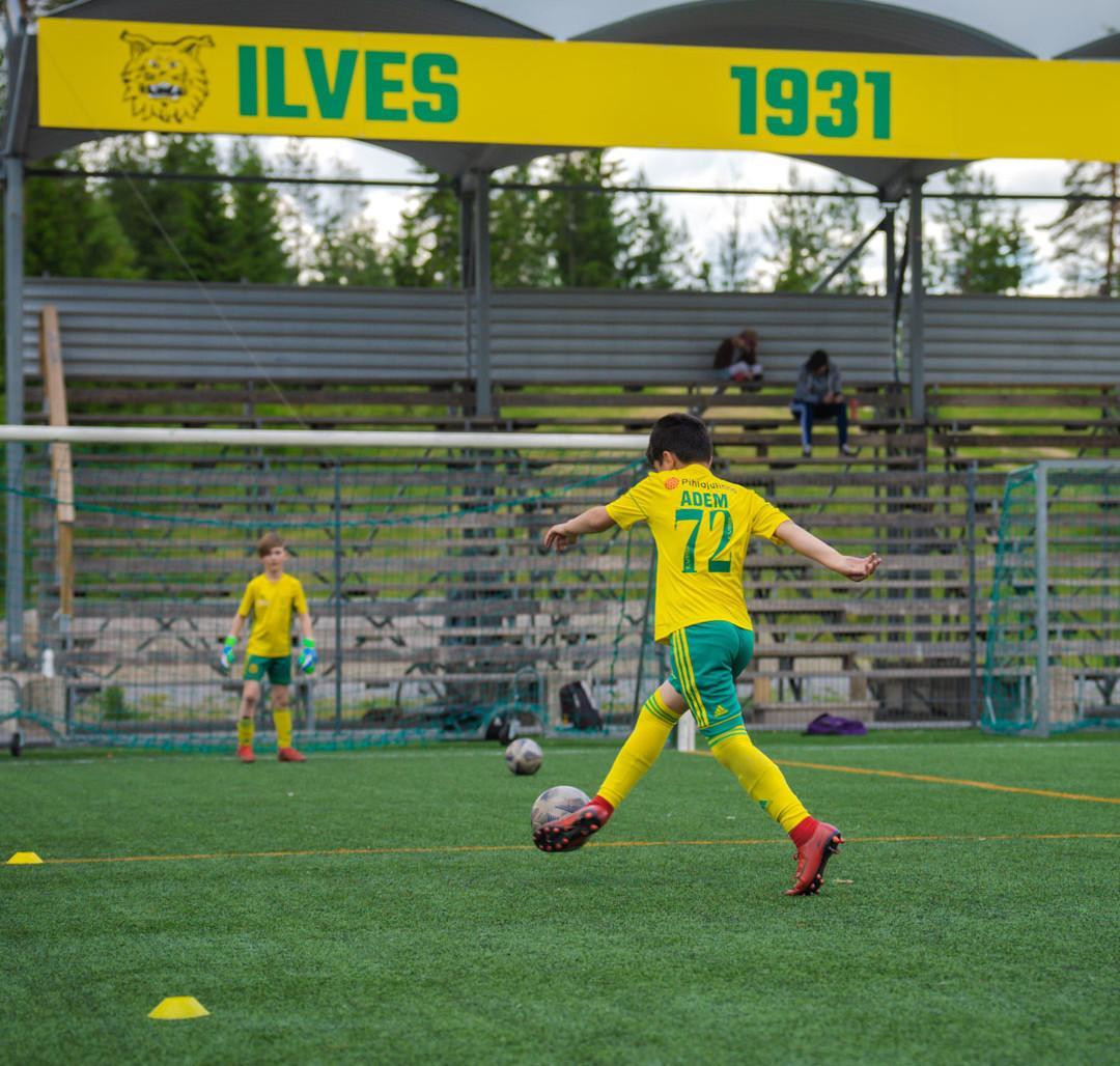 Ilves ry:ssä pelaava poika potkaisee jalkapalloa.