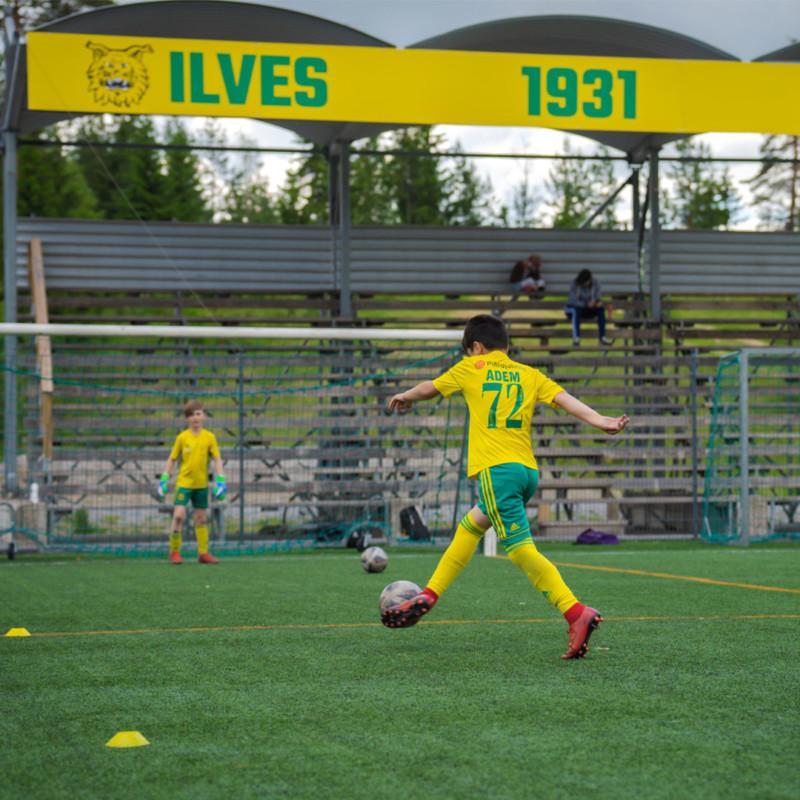 Ilves ry:ssä pelaava poika potkaisee jalkapalloa.